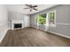 Cozy living room with fireplace, neutral paint, wood-look floors, and a large sunny window at 2923 Akron St, East Point, GA 30344