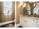 Elegant powder room boasts an oval mirror, marble countertop, decorative wall sconce, and dark hardwood floors at 927 Berkshire Ne Rd, Atlanta, GA 30324