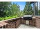 Cozy outdoor kitchen area featuring a built-in grill, brick surround and picturesque views of the surrounding greenery at 927 Berkshire Ne Rd, Atlanta, GA 30324