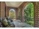 Relaxing covered porch features brick arches, iron railing, and comfortable seating for enjoying the outdoors at 927 Berkshire Ne Rd, Atlanta, GA 30324