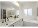 Bright bathroom features a double sink vanity, bathtub, and glass-enclosed shower at 1010 Graystone Xing, Alpharetta, GA 30005