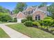 Beautifully landscaped brick home with mature trees, green lawn and attached garage at 1010 Graystone Xing, Alpharetta, GA 30005