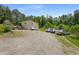 Long gravel driveway leading to a home with ample parking space, surrounded by trees and greenery at 212 Postell Rd, Dallas, GA 30157