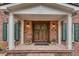 Inviting entryway with a brick porch, wood double doors, and classic white columns at 2592 River Oak Dr, Decatur, GA 30033