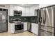 Close-up of renovated kitchen with stainless steel appliances, white cabinetry and emerald backsplash at 600 Oakmont Hl, Duluth, GA 30097