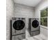Bright laundry room featuring modern washer and dryer, decorative wallpaper and marble flooring at 600 Oakmont Hl, Duluth, GA 30097