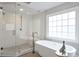 Bathroom featuring glass enclosed shower and modern soaking tub by a large window at 1064 Saint James Xing, Brookhaven, GA 30319