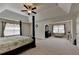 Large primary bedroom with a decorative tray ceiling, ceiling fan, and sitting area for relaxation at 1200 Bar Harbor Pl, Lawrenceville, GA 30044