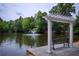 Relaxing pond view with a fountain, a pergola, seating and lush surrounding greenery at 2303 Waters Edge Trl, Roswell, GA 30075