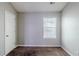 Bedroom features neutral paint, carpet floors, window with blinds, and door to the side at 6285 Polar Fox Ct, Riverdale, GA 30296
