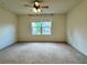 Large bedroom with carpet floors, ceiling fan, and plenty of natural light from the large window at 1606 Larkspur Trl, Conyers, GA 30012
