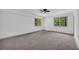 Spacious bedroom with neutral carpet, ceiling fan, and large windows overlooking the yard at 5200 Beechwood Forest Ct, Lithonia, GA 30038