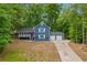 Charming two-story blue home featuring a welcoming front porch and an attached two-car garage, nestled among lush trees at 5200 Beechwood Forest Ct, Lithonia, GA 30038