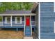 A close-up of the front of a two-story blue house, showing the front porch and a bright red front door at 5200 Beechwood Forest Ct, Lithonia, GA 30038
