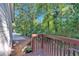 Charming wooden back porch and railing surrounded by a lush green backdrop and a peek at the driveway at 54 Mildred Ct, Dallas, GA 30157