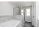 Bright bathroom featuring a tub with gray tile backsplash and a glass-enclosed shower at 407 Newland Way, Acworth, GA 30102