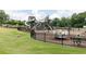 Playground with climbing structures and swings, fenced in for safety, surrounded by a lush green lawn and mature trees at 407 Newland Way, Acworth, GA 30102