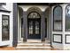 Elegant front entrance with stone steps, striking black double doors, and sophisticated architectural details at 1066 Fairway Valley Dr, Woodstock, GA 30189