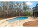Gorgeous in-ground pool and waterfall feature, accented by stone tile and a wooded backdrop at 1066 Fairway Valley Dr, Woodstock, GA 30189