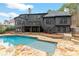 In-ground pool and waterfall feature, surrounded by natural stone tiles and a private, wooded backdrop at 1066 Fairway Valley Dr, Woodstock, GA 30189