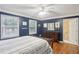 Comfortable bedroom with wood floors, a ceiling fan, windows, and dark blue walls with white trim at 4856 Saddlerun Ln, Powder Springs, GA 30127