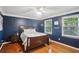Stylish bedroom with blue walls, wood floors, ceiling fan, and natural light from the windows at 4856 Saddlerun Ln, Powder Springs, GA 30127