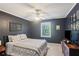 Comfortable bedroom with dark blue walls, a ceiling fan, and a cozy patterned comforter at 4856 Saddlerun Ln, Powder Springs, GA 30127