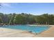 Large community pool with multiple lap lanes, lounge chairs, clear blue sky, and mature trees at 4856 Saddlerun Ln, Powder Springs, GA 30127