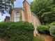 Brick home exterior with arched window and brick chimney surrounded by lush landscaping and trees at 365 Falling Creek Bnd, Duluth, GA 30097
