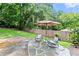 Cozy backyard stone patio featuring an umbrella, seating, and lush green surroundings at 4855 Kendall Ct, Atlanta, GA 30342