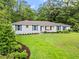 Charming one-story home with white brick, blue shutters, and a lush green lawn surrounded by mature trees at 4855 Kendall Ct, Atlanta, GA 30342