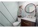 Stylish powder room with a modern vanity, round mirror, and decorative wall paneling at 4855 Kendall Ct, Atlanta, GA 30342