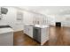 Open concept kitchen with stainless steel dishwasher, quartz countertops, island seating and view into the living space at 517 Hyde Ridge Trl, Loganville, GA 30052