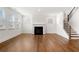 Bright living room with hardwood floors, a fireplace, and a staircase with wood railings and white risers at 517 Hyde Ridge Trl, Loganville, GA 30052