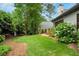 Private backyard featuring a lush lawn, mature trees, landscaped garden beds, and a brick patio at 2715 Woods Ridge Dr, Alpharetta, GA 30022