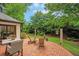 Backyard patio area with chairs and table, surrounded by lush greenery and a well-manicured lawn at 2715 Woods Ridge Dr, Alpharetta, GA 30022