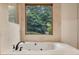 A luxurious soaking tub with jets is set beneath a window with a view of lush greenery at 2715 Woods Ridge Dr, Alpharetta, GA 30022
