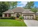 Charming single-story home with a well-manicured lawn, brick accents, and a two-car garage, surrounded by lush greenery at 2715 Woods Ridge Dr, Alpharetta, GA 30022