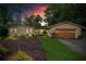 Charming single-story home at dusk with warm lighting, attached garage, and lush, landscaped front yard at 4040 Summit Dr, Marietta, GA 30068