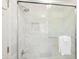 Modern shower with large white marble tiles, a glass enclosure, and a convenient built-in shelf for storage at 10310 Amberside Ct, Roswell, GA 30076