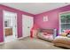 Bedroom with pink walls featuring a crib and a comfy chaise lounge by the window at 1411 Primrose Park Rd, Sugar Hill, GA 30518