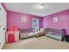 Bedroom with pink walls featuring two cribs and a comfy chaise lounge by the window at 1411 Primrose Park Rd, Sugar Hill, GA 30518