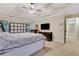 Bright bedroom with neutral tones featuring a ceiling fan, closet space, and wall-mounted television at 1411 Primrose Park Rd, Sugar Hill, GA 30518