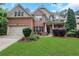 Charming two-story brick home boasts a lush lawn and manicured landscaping, offering curb appeal at 1411 Primrose Park Rd, Sugar Hill, GA 30518