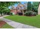 Attractive two-story brick home with lush green lawn, mature landscaping, and a side-entry two-car garage at 1411 Primrose Park Rd, Sugar Hill, GA 30518