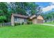 View of the front of the house with a green lawn and mature trees and shrubs in the background at 8350 Gledstone Way, Fairburn, GA 30213