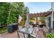 Backyard view of an outdoor patio with a pergola, dining set, grill, and wooded landscape beyond at 3480 Arbroath Dr, Douglasville, GA 30135
