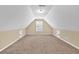 A spacious carpeted attic with a window, white ceiling, and two access doors at 3865 Pointer Rd, Loganville, GA 30052