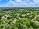 A scenic aerial view showcases a charming neighborhood nestled amidst a canopy of green trees on a sunny day at 2910 Waverly Place Dr, Dacula, GA 30019