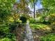 Brick pathway in backyard, surrounded by mature trees and verdant foliage at 2910 Waverly Place Dr, Dacula, GA 30019